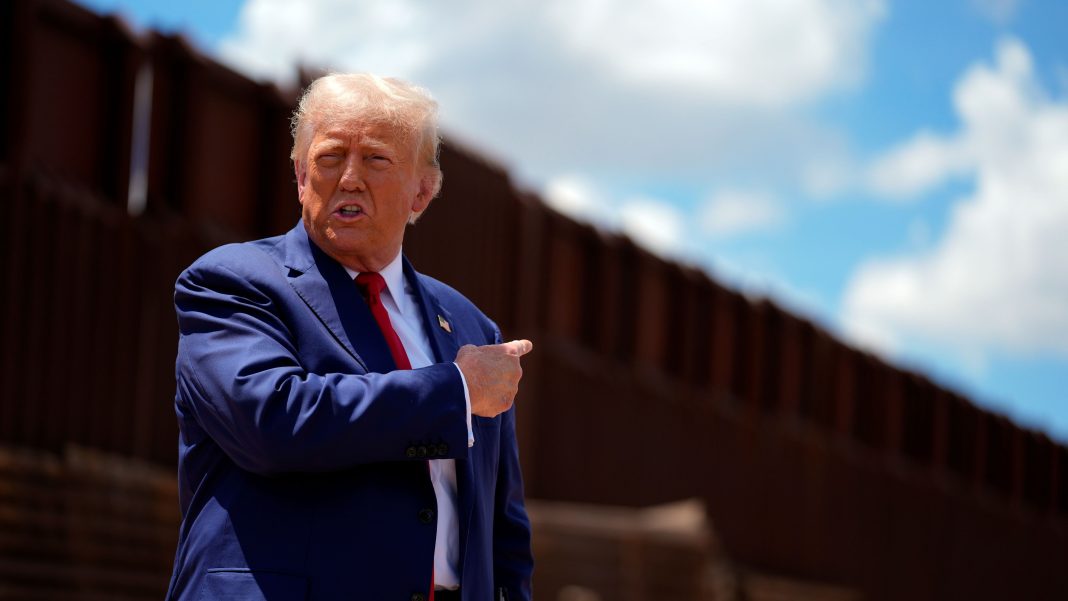 Former President Donald Trump gestures near the U.S.–Mexico border wall. Political analysts say immigration and the renewed “build the wall” messaging may not provide the same electoral advantage for Republicans in the upcoming midterm elections, suggesting the issue could have a more limited impact on voters than in previous campaigns. Photo credit: AP photo by Evan Vucci